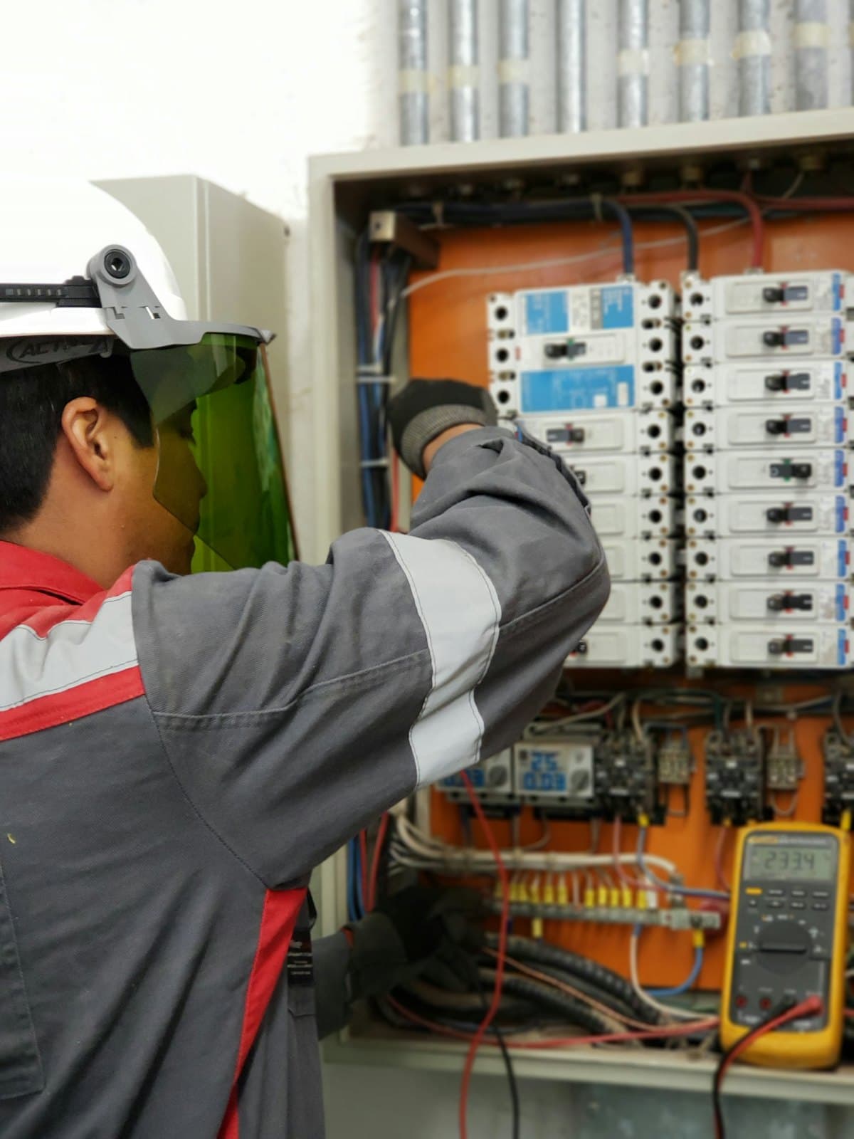 Técnico con protección facial frente a un tablero de interruptores